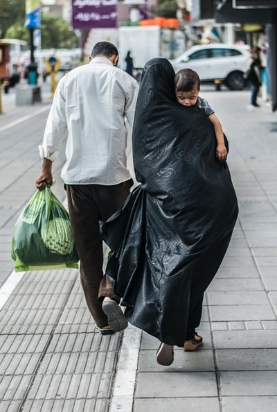 一个穿着黑衣服的女人手里拿着一个绿色的塑料袋